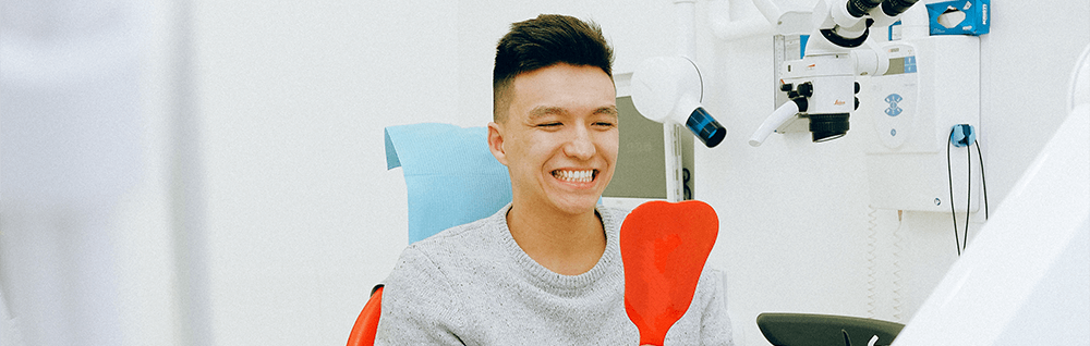 Saubere Zähne – Lachender Mann mit Spiegel